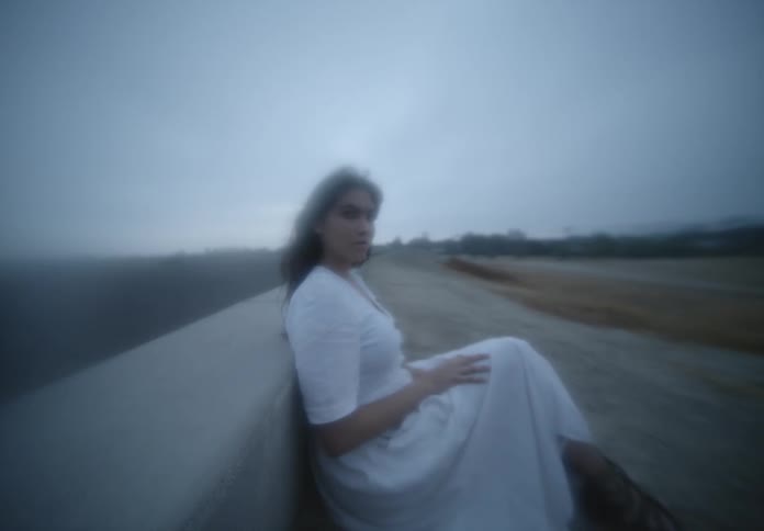 A woman sits on a bench on the side of a road