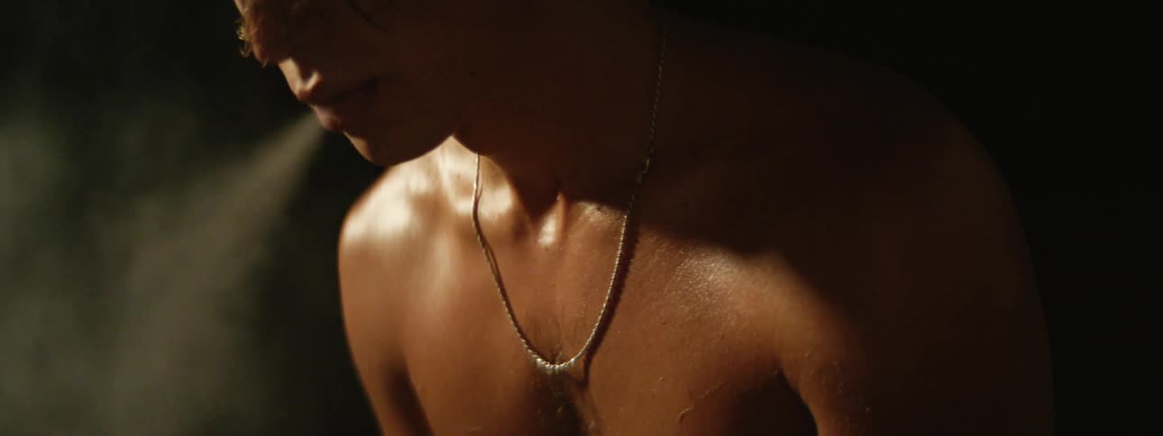 Shirtless man with necklace smoke a cigarette