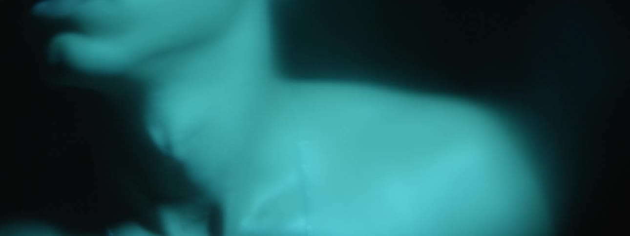 Barechested young man turn his head left and right under moving blue lights