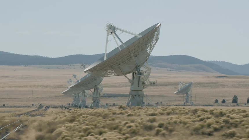 An array of giant satellites set by train tracks in a remote dry field