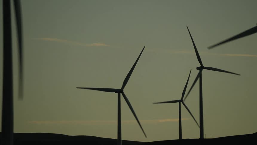 Wind turbines on a ridge silhouetted against a sunset sky