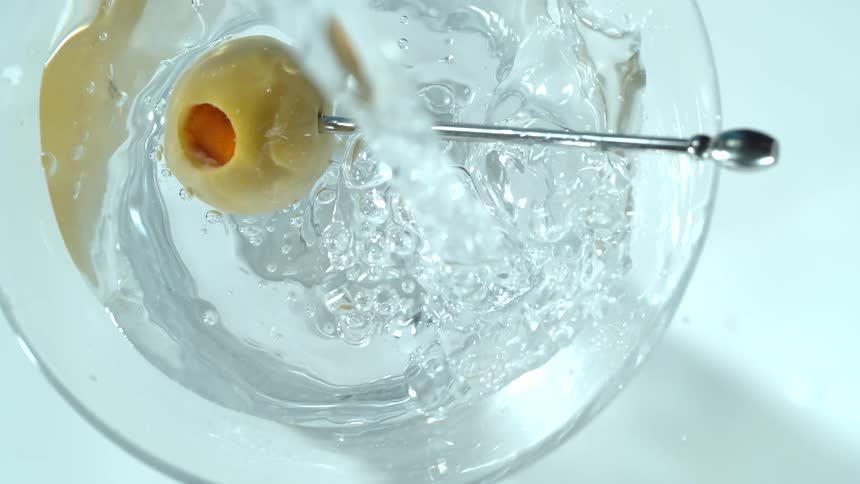 Olive stick falls into a glass of water