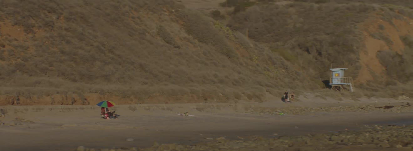 People are walking along a desert near a hill