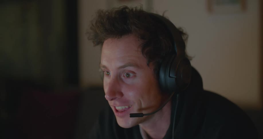 Man wearing a headphone set with an attached microphone laughs and talks