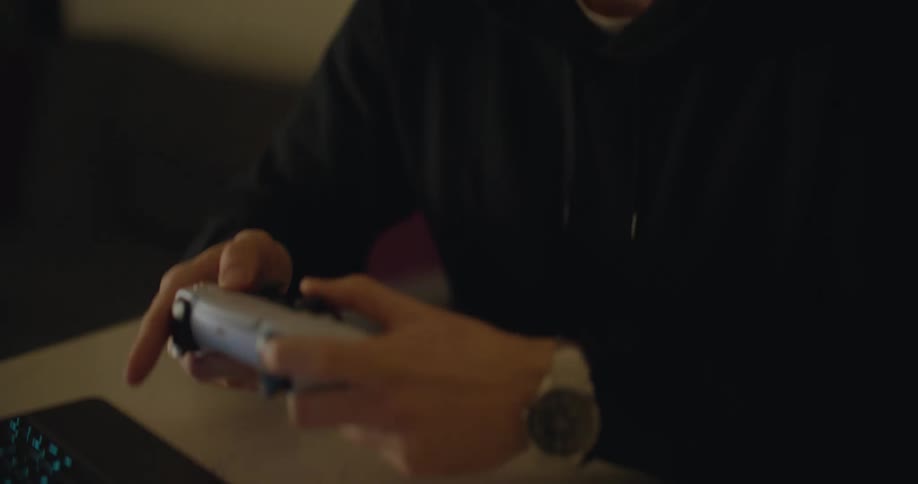 A man uses a controller to play a video game on his laptop