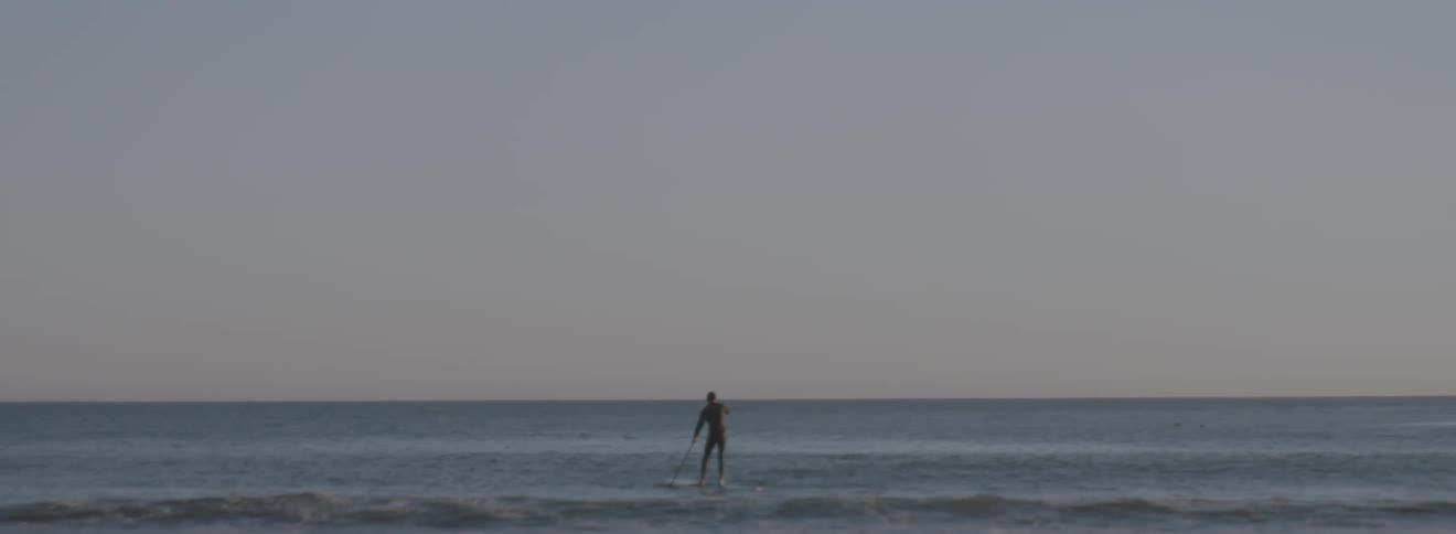A man is paddling out on a board into the ocean