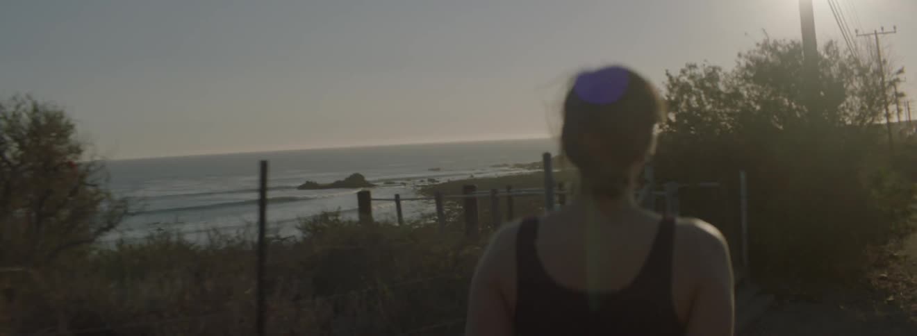 A woman walks at sunset near the water