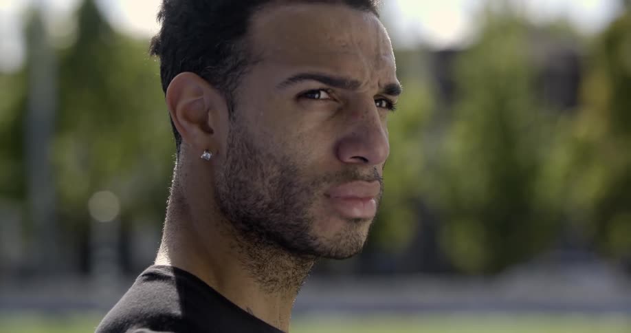 A man in a black shirt turns his head and looks around