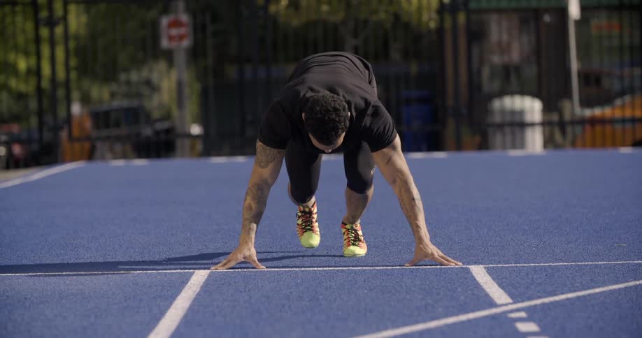 A man readies himself to start a run on an athletic track