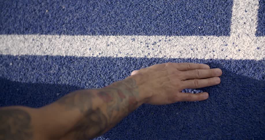 A hand places down on a running track