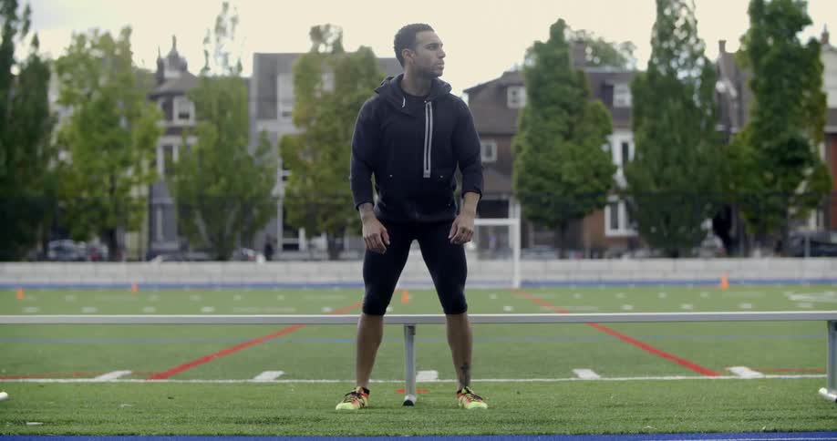 A man sits on a bench at a blue track