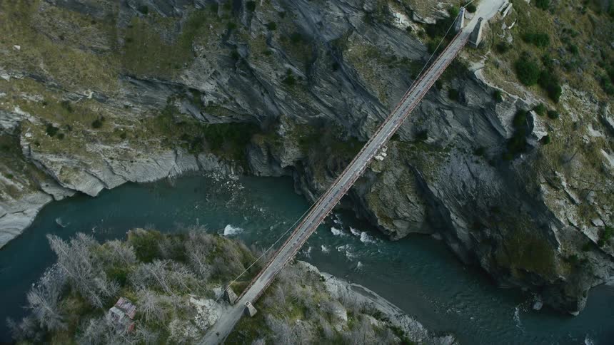A foot bridge extending across rock cliffs high above a river
