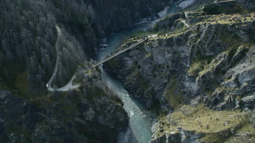 An aerial view of a bridge crossing a river in a mountain range