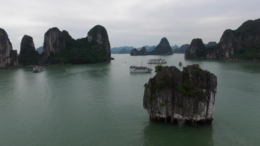 Boats are anchored all around the large rocks in the water