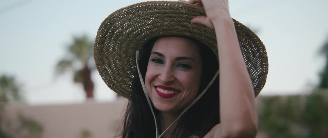 A woman in a sunhat turning and smiling