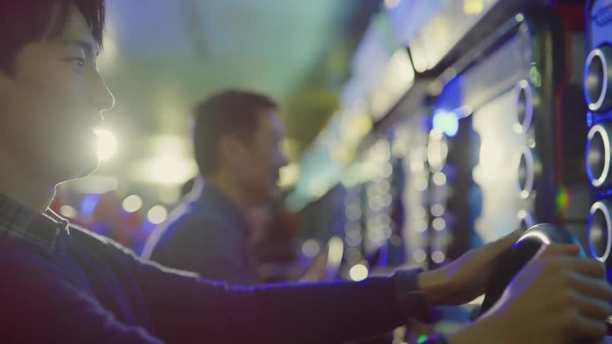 Group of friends playing racing video games inside an arcade