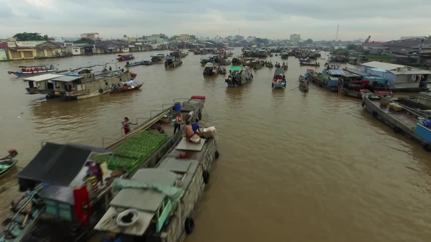 Aerial view of boats and barges on the brown water of a river in a third world city