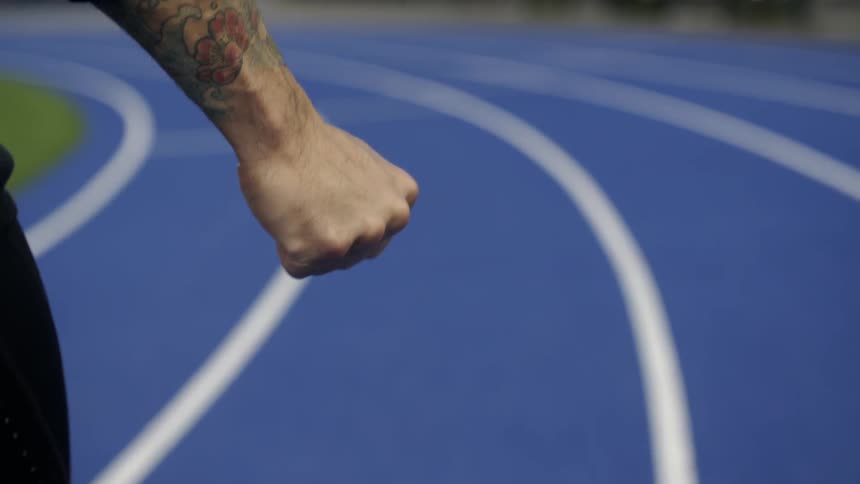 A man clenching his fist as he walks along a race track