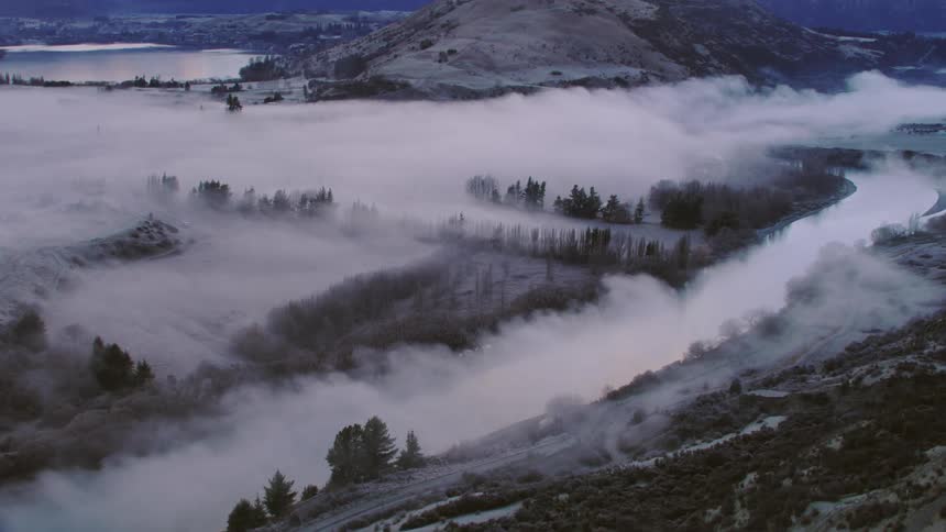 An aerial view of fog over a riverbed and valley