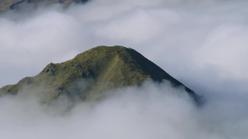 A mountain top peaking up out of thick cloud cover