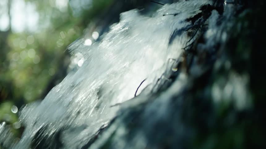 Water flows down a slope splashing into a stream on a sunny day