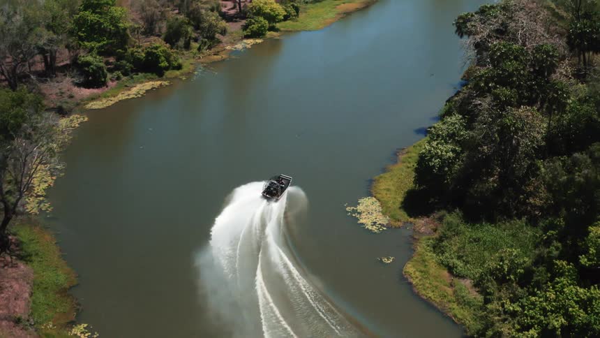 An aerial view of a boat driving down a river