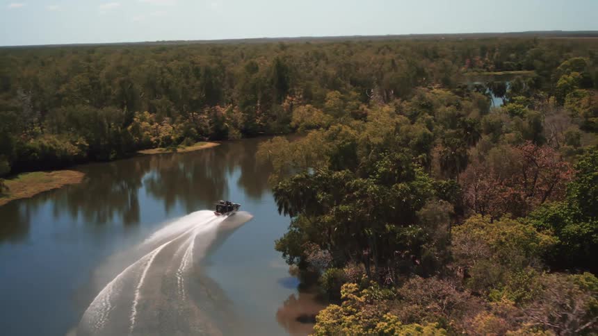 An aerial view of a boat moving down a river