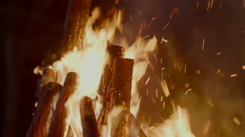 Burning embers spark from a campfire