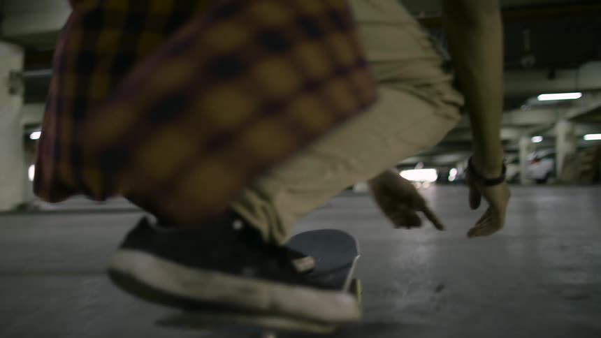 Two men are doing skateboard tricks in a parking garage