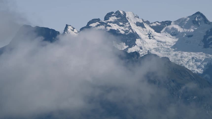 Clouds moving in front of a snow covered mountain range