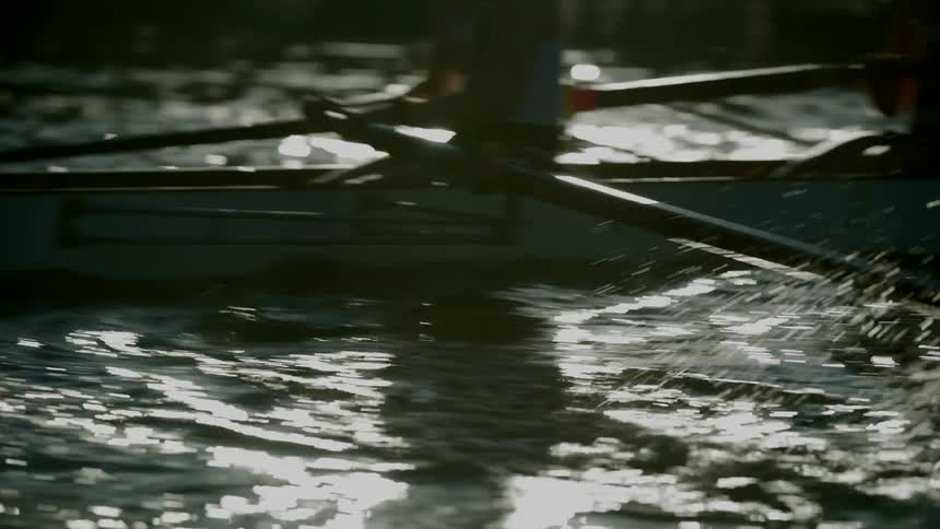 Three women row a boat on a lake