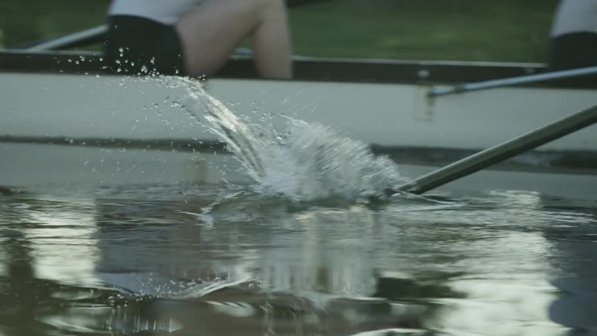A group of friends paddles a boat on the still lake