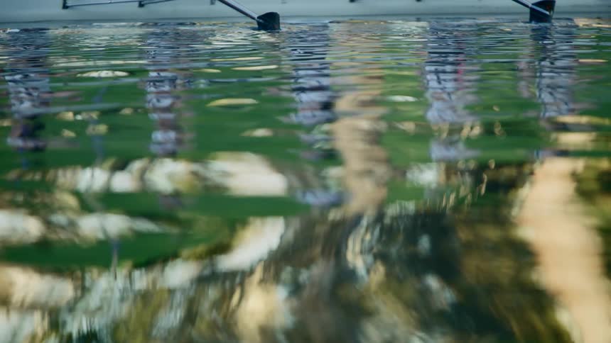 Women in a boat holding oars getting ready to paddle is reflected in the water