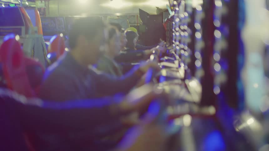 Group of friends playing racing video games inside an arcade