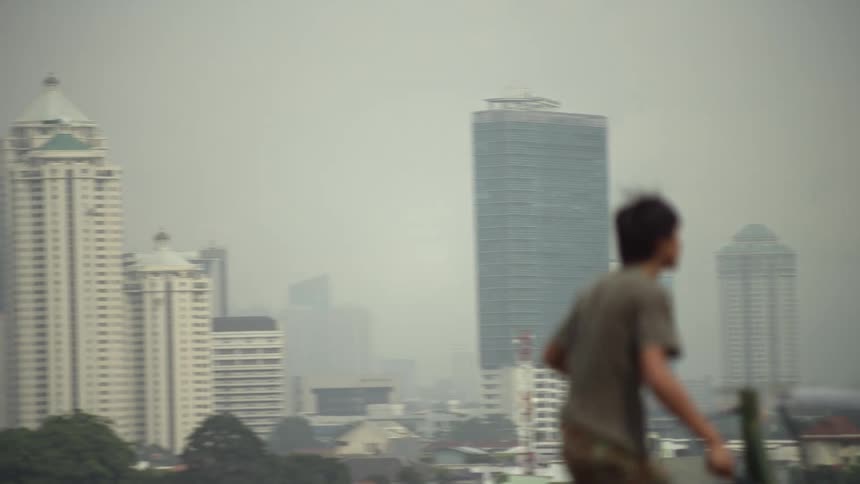 A man is hitting a tennis ball with the city as a backdrop