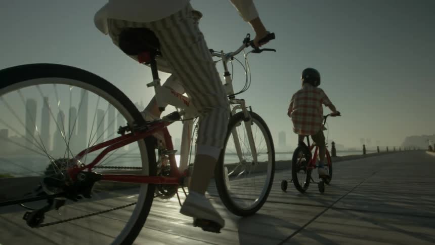 A parent and child ride their bikes on the pier