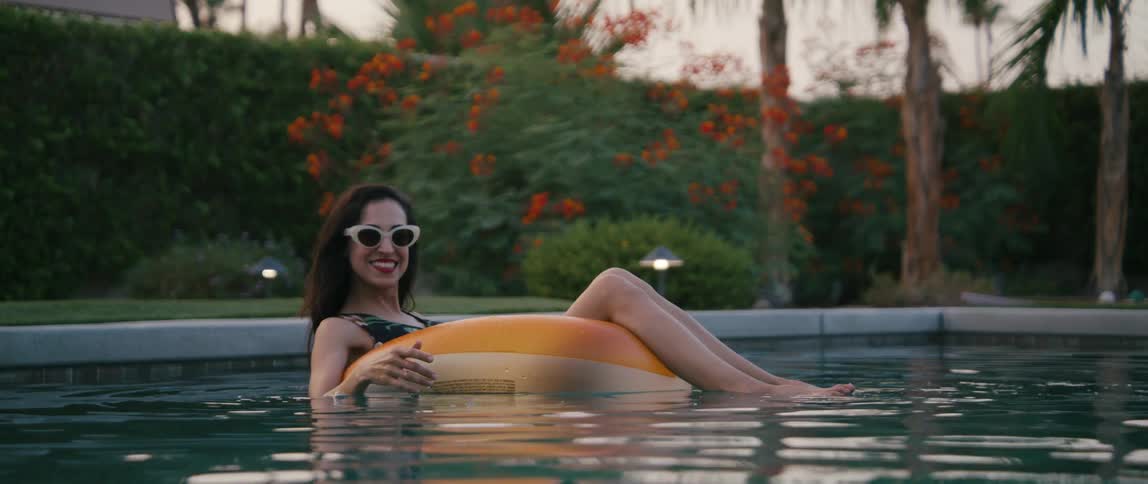 A woman is smiling while floating on a tube in a pool