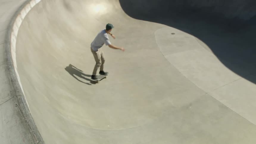 A teenage boys skateboards up the edge of a large skateboard ramp