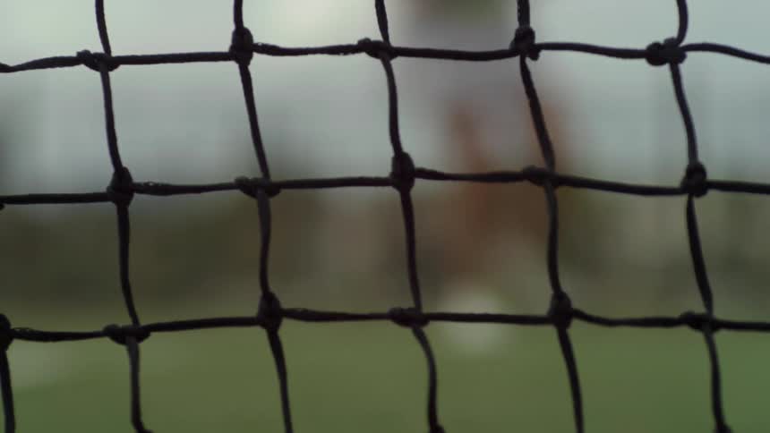 A net with people playing tennis in the background