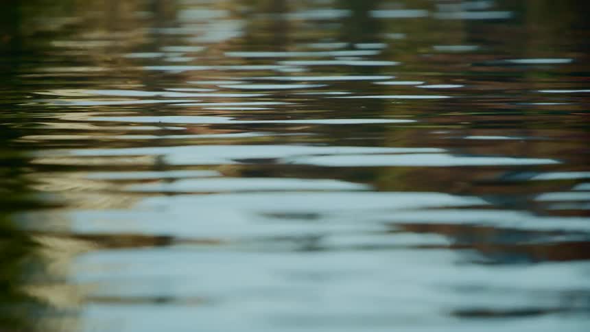 Rippling flowing water reflects surroundings and blue sky