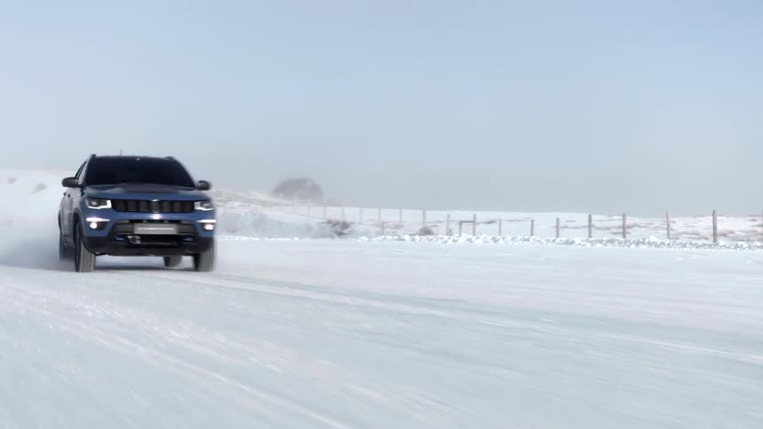 Blue suv car drives on snowy field next to fences
