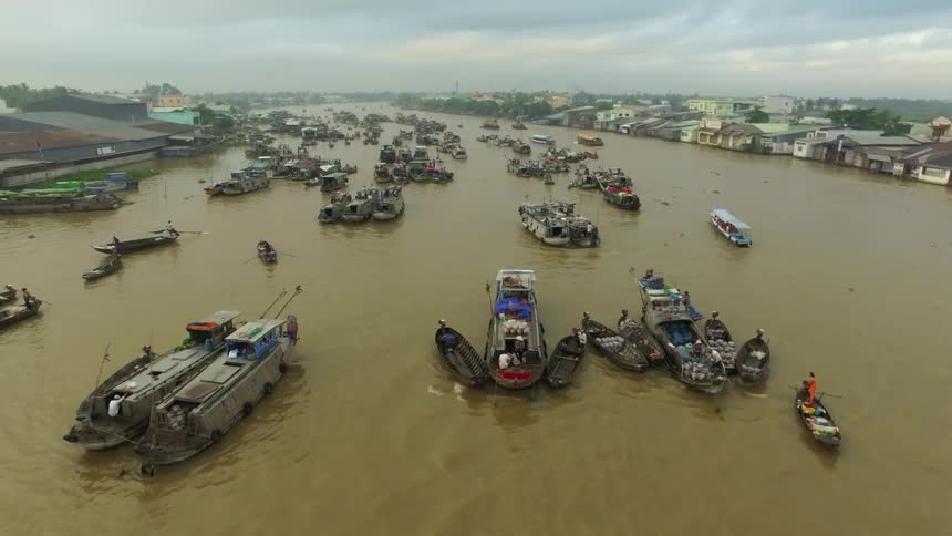 A large river contains numerous boats that are in motion or are moored together