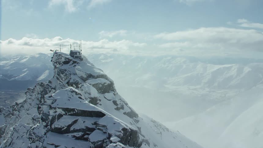 A building with solar panels sits on the peak of a snow covered mountain