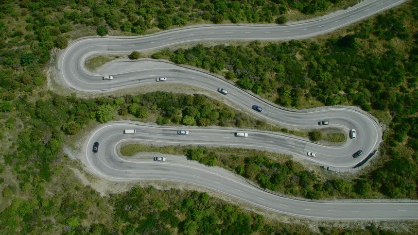 Aerial view of cars driving up and down a twisting road on the mountains