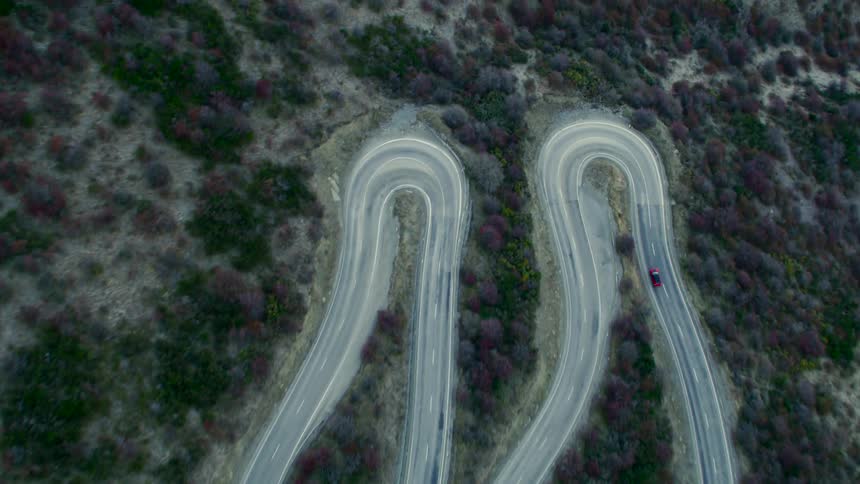 Aerial view of red car driving on winding road
