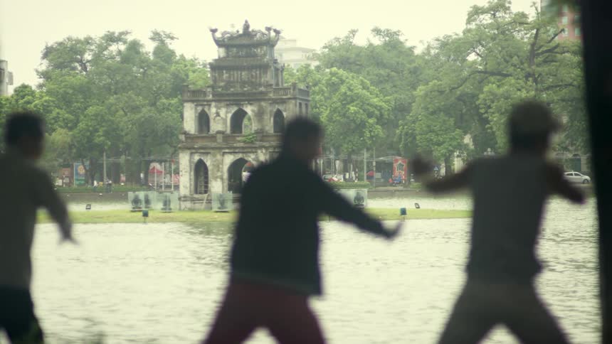 Silhouette of a group of men practicing tai chi in front of a temple on a park