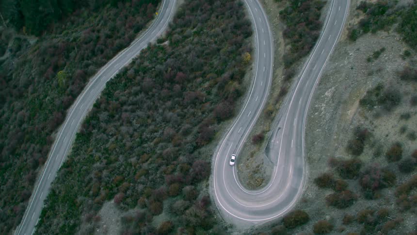 An aerial view of a car driving up a mountain road