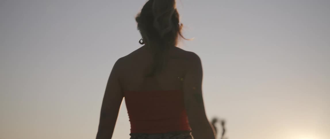 Young woman standing on the desert spinning in front of the sunset