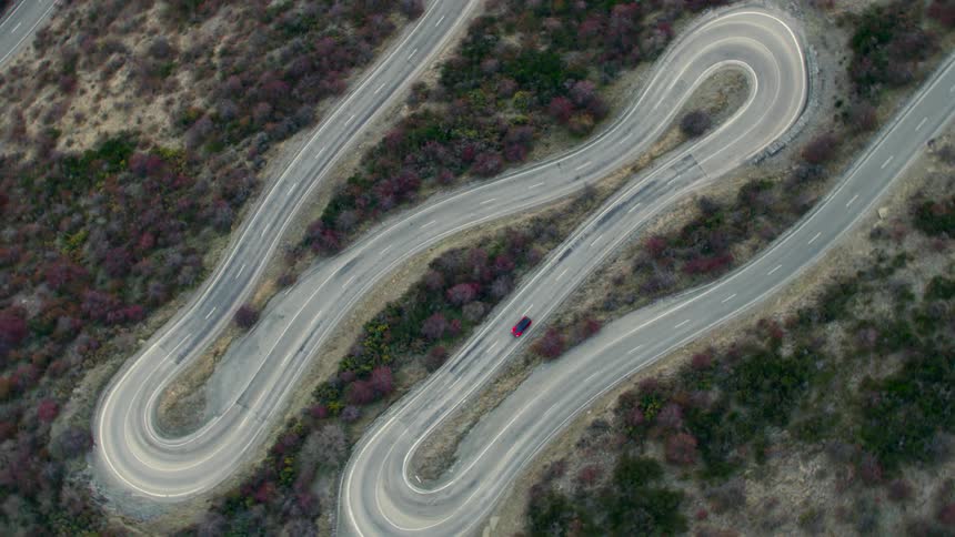 An aerial view of a car driving on a twisty road