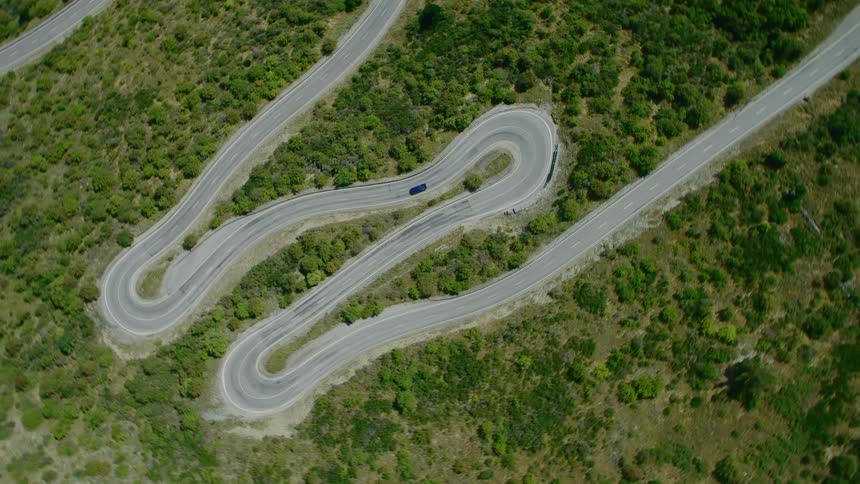 Aerial view of car driving on winding road in field